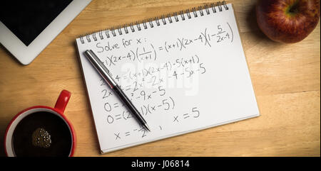 Gleichungen auf schwarzem Hintergrund gegen Aufwand Notizblock und Stift Stockfoto