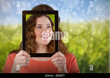 Frau mit digital-Tablette vor ihr Gesicht gegen grüne Wiese Stockfoto