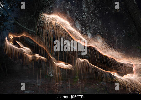 BRASILIANISCHE MITTELLAND, Brasilien: Feuerwerk haben verwendet, um einzigartige Kunstwerke schaffen, die Vergänglichkeit des Lebens darstellt. Die Serie namens "Einheiten" zeigt feurig orange wirbelt und Streifen gegen natürliche Einstellungen überlagert.  Lichtmuster lässt sich über dem Wasser tanzen, Felsen und sand sowie mächtigen alten Bäumen in ein spektakuläres Feuerwerk. Brasilianische Fotograf Vitor Schietti (30) schuf dieses leuchtende Kunstwerk in seinem Heimatland mit der brasilianischen Mittelland als seinen Hintergrund. Stockfoto