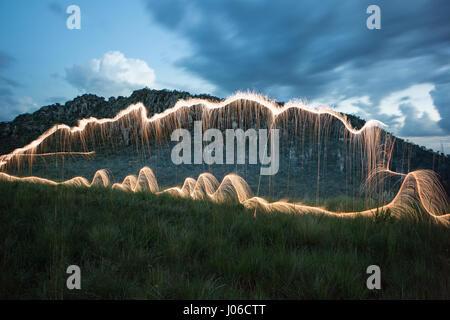 BRASILIANISCHE MITTELLAND, Brasilien: Feuerwerk haben verwendet, um einzigartige Kunstwerke schaffen, die Vergänglichkeit des Lebens darstellt. Die Serie namens "Einheiten" zeigt feurig orange wirbelt und Streifen gegen natürliche Einstellungen überlagert.  Lichtmuster lässt sich über dem Wasser tanzen, Felsen und sand sowie mächtigen alten Bäumen in ein spektakuläres Feuerwerk. Brasilianische Fotograf Vitor Schietti (30) schuf dieses leuchtende Kunstwerk in seinem Heimatland mit der brasilianischen Mittelland als seinen Hintergrund. Stockfoto