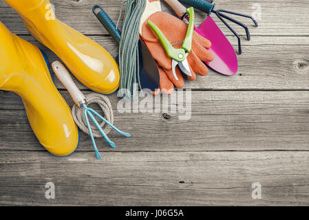 Gummistiefel und Gartengeräte. Stilleben auf Holzbrettern. Stockfoto