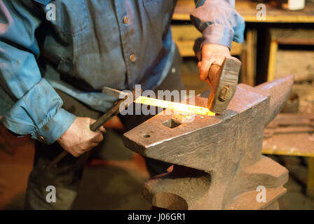 Herstellung von Hufeisen. Männliche Arbeiter mit einer Zange und Hammer Hufeisen zu machen. Stockfoto