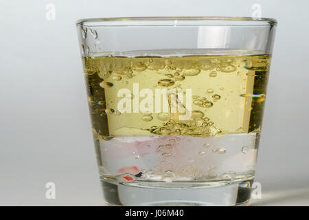 Glas mit Tropfen von farbigen Bläschen im Wasser und Öl Stockfoto