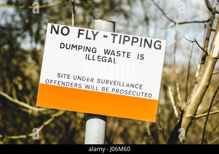 Ein Zeichen in England, UK, die Warnung, dass dumping von Müll in der Gegend ist illegal und Zuwiderhandlungen werden strafrechtlich verfolgt. Überwachung-Website. Stockfoto