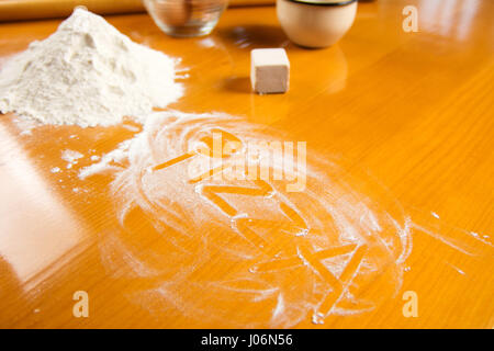 Wort-Pizza in Mehl auf einem Küchentisch geschrieben Stockfoto