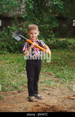 kleine lustige junge mit Schaufel im Garten Stockfoto