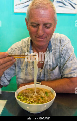 Vertikale Porträt eines Touristen Essen eine Schale mit Pho in Vietnam. Stockfoto