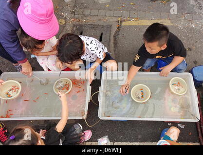 KAOHSIUNG, TAIWAN--15. Oktober 2016: kleine Kinder fangen kleine Goldfische. Dies ist eine beliebte Kinder Aktivität auf dem freien Markt. Stockfoto