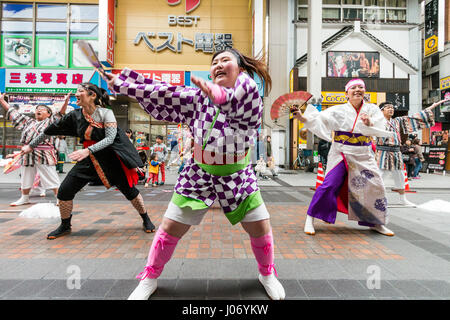 Japan, Kumamoto, Hinokuni Yosakoi Dance Festival. Teenage Frau Tänzer, hält das Gebläse, in Karomuster yukata, tanzen vor der Viewer. Close Up. Stockfoto