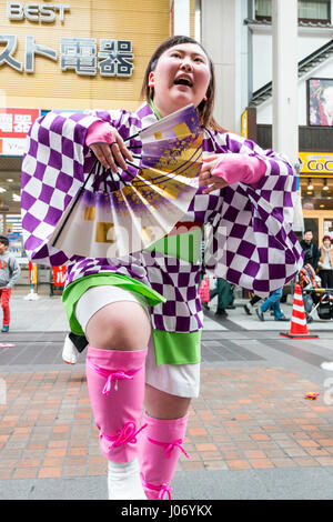 Japan, Kumamoto, Hinokuni Yosakoi Dance Festival. Teenage Frau Tänzer, hält das Gebläse, in Karomuster yukata, tanzen vor der Viewer. Close Up. Stockfoto