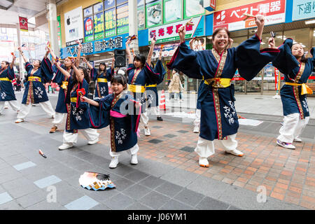 Hinokuni Yosakoi Dance Festival. Dance Team in Dunkelblau yukata mit kleinen Kindern vor Tanzen und Holding naruko, in der Einkaufspassage Stockfoto