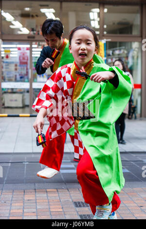 Japan, Kumamoto, Hinokuni Yosakoi Dance Festival. Mädchen tanzen in Grün und Rot Yukata, und mit naruko, vogel Klöppel. - Nahaufnahme, Auge - Kontakt. Stockfoto