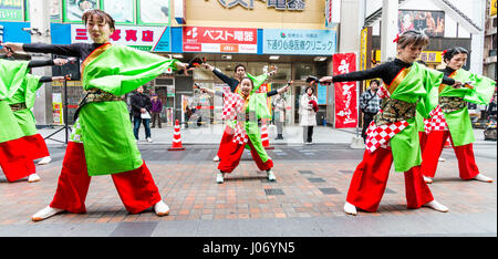 Kumamoto, Japan, Hinokuni Yosakoi Tanzfestival. Team mit Kind, Mädchen, tanzen in der Mitte, alles in rot und grün Yukata. Stockfoto