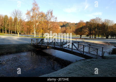 Blick über den zugefrorenen Teich mit Holzbrücke auf dem 6. Loch, East Course Sundridge Park Golf Club, Bromley, Kent, England Stockfoto