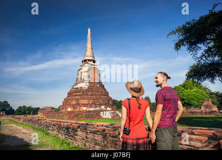 Junges Paar in roter Kleidung mit Fotokamera, Blick auf alten zerstörten Wat Mahathat in Ayutthaya, Thailand Stockfoto