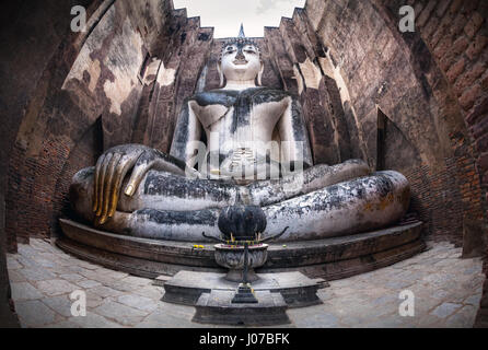 Riesige Buddha-Statue Phra Achana in Wat Si Chum in grau bedecktem Himmel in Sukhothai Historical Park, Thailand anrufen Stockfoto