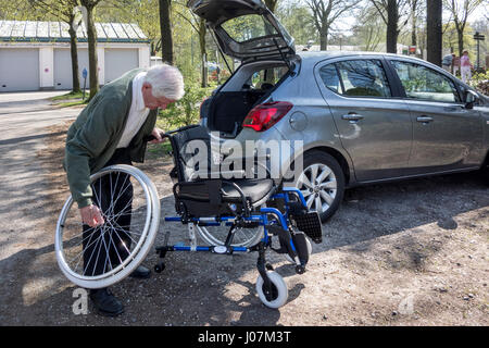 Senior woman Montage / Demontage Rollstuhl von körperlich behinderten älteren Frau vor Auto am Parkplatz Stockfoto