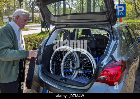 Senior woman Montage nicht demontiert Rollstuhl von körperlich behinderten älteren Frau im Kofferraum eines Autos am Parkplatz für Behinderte Stockfoto