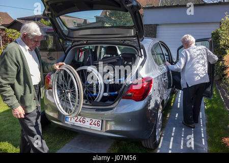 Ältere Mann Montage nicht demontiert Rollstuhl von körperlich behinderten älteren Frau im Kofferraum eines Autos zu Hause vor dem Schlafengehen für eine Fahrt Stockfoto