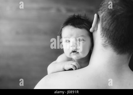 Neugeborenes Baby und Papa. Glück-Baby auf die Väter Hände. Vater mit Baby über die Schulter schauen. Dunklen Hintergrund. schwarz / weiß Foto. Stockfoto