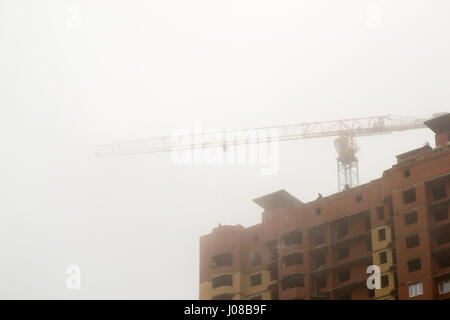 der Kran im Nebel auf den Bau von Häusern Stockfoto