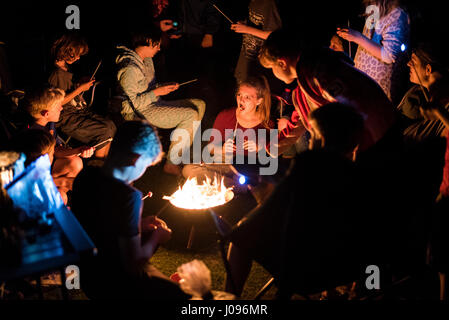 Kinder Rösten Marshmallows auf Stöcke um ein Feuer beim camping entfernt Stockfoto