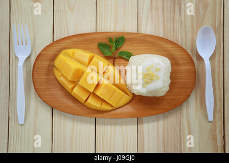 Traditionelle Thai Dessert Mango mit klebrigem Reis mischen Kokosmilch in hölzerne Schale auf Lebensmittel-Tabelle. Stockfoto