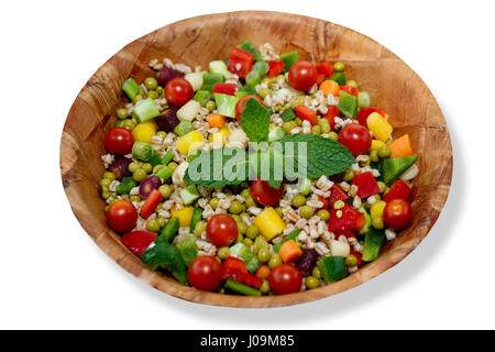 Salat mit Paprika, Dinkel, Erbsen, Frühlingszwiebeln und Regenbogen-Baby-Karotten, dekoriert mit Minze in verwittertem Holz Bambusschüssel, isolat Stockfoto