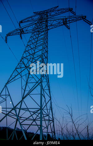 große elektrische Energie Turm bei Sonnenuntergang mit einem gelben Mond im Hintergrund Stockfoto