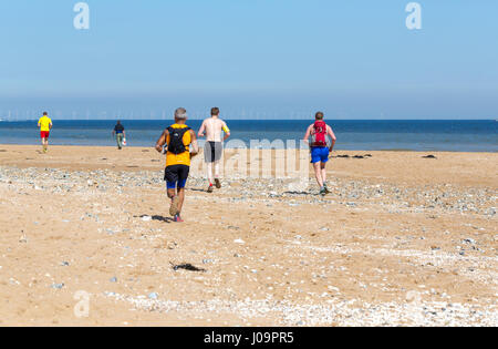 Gruppe von echten Jugendliche Frauen und Männer laufen am Strand in Margate, Kent, England Stockfoto