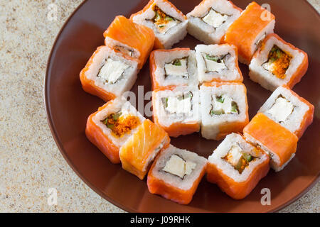 Sushi set auf einem Stein Hintergrund - Philadelphia klassische Rollen, Käse Lachs roll und Rollen Jamaika mit eingelegtem Ingwer und Sojasauce. Stockfoto