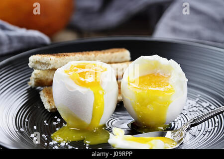 Weich gekochtes Ei mit Toast Soldaten und Früchten im Hintergrund. Extrem geringe Schärfentiefe mit selektiven Fokus. Stockfoto