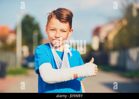 Schelmische Junge mit gebrochenen Hand verletzt nach Unfall OK Anzeichen Stockfoto