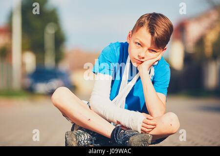 Schelmische Junge mit gebrochenen Hand Verletzte nach Unfall während der Sommersportarten. Stockfoto