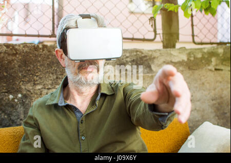 Senior woman mit virtueller Realität im Hinterhof Stockfoto
