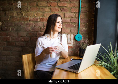 Porträt einer jungen schön Geschäftsfrauen Kaffeegenuss während der Arbeit auf tragbaren Laptop-Computer, charmante Studentin mit Net-Buch während sitt Stockfoto