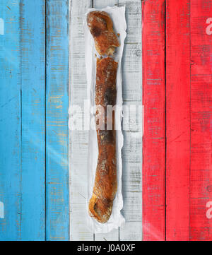Ein traditionelles französisches Baguette über einen Rusticwooden Tisch mit den Farben der Flagge von Frankreich. Stockfoto