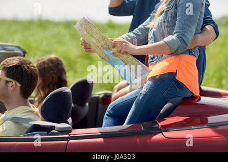 Glückliche Freunde mit Karte im Cabrio fahren Stockfoto