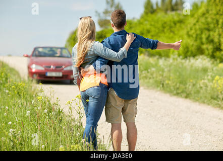 paar Trampen und Anhalten von Autos auf Land Stockfoto