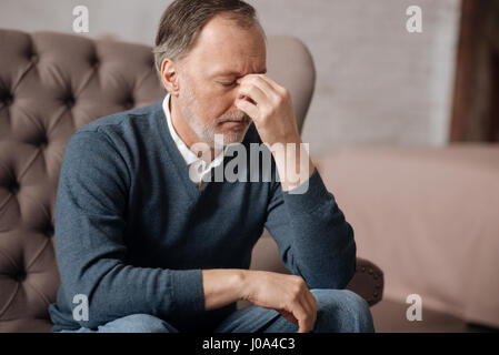 Kranken Kopfschmerzen. Porträt des alten Mannes Nasenrücken mit den Fingern berührt, während er schreckliche Kopfschmerzen. Stockfoto