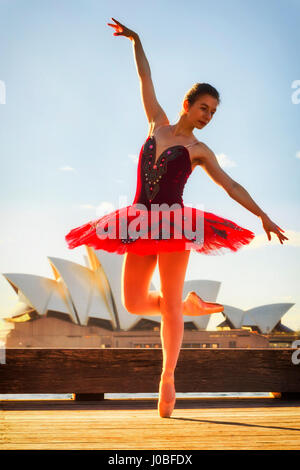 Jungen Ballerina in rot passen Konzert Tutu Dehnung unter Punkt Schuhe unter Punkt Position im Freien auf der Straße in Sydney im warmen Licht der aufgehenden Sonne wieder Stockfoto