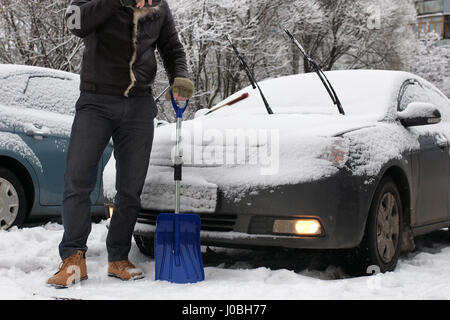 Morgendliche Schneeräumung - ein Mann reinigt das Auto vor Die Reise -  Kaltstart im Winter Stockfotografie - Alamy