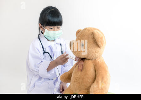 Kind spielt Arzt mit Stethoskop und Teddybär Stockfoto
