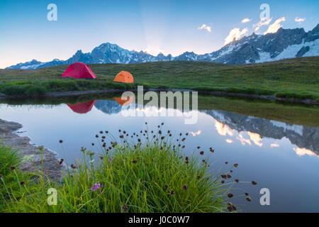 Camping Zelte auf den grünen Wiesen umgeben von Blumen und Alpensee, Mont De La Saxe, Courmayeur, Aostatal, Italien Stockfoto