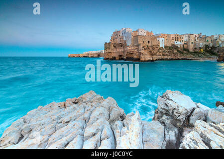 Türkisfarbenes Meer in der Abenddämmerung, umrahmt von der Altstadt thront auf den Felsen, Polignano a Mare, Provinz Bari, Apulien, Italien Stockfoto