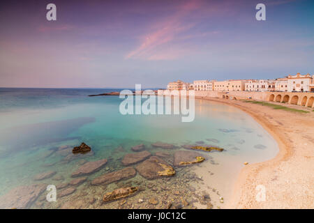 Türkisfarbenes Meer umrahmt, der Strand und die mittelalterliche Altstadt bei Sonnenuntergang Gallipoli, Provinz Lecce, Apulien, Italien Stockfoto