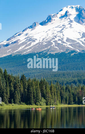 Kanus und Ruderboot auf den stillen Wassern der Trillium Lake mit Mount Hood, Teil der Kaskadenkette, Oregon, USA Stockfoto