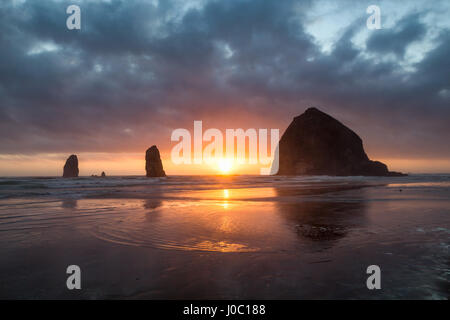 Sonnenuntergang hinter Haystack Rock in Cannon Beach auf der pazifischen Nordwestküste, Oregon, USA Stockfoto