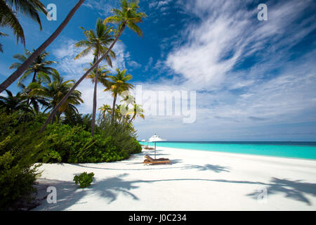 Liegestühle im Schatten der Sonnenschirm am tropischen Strand, Malediven, Indischer Ozean, Asien Stockfoto