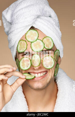 Lustiger Mann empfangen Gesichtsmaske Gurke. Das Gesicht des Mannes kosmetischen Verfahren. Pflege selbst Stockfoto